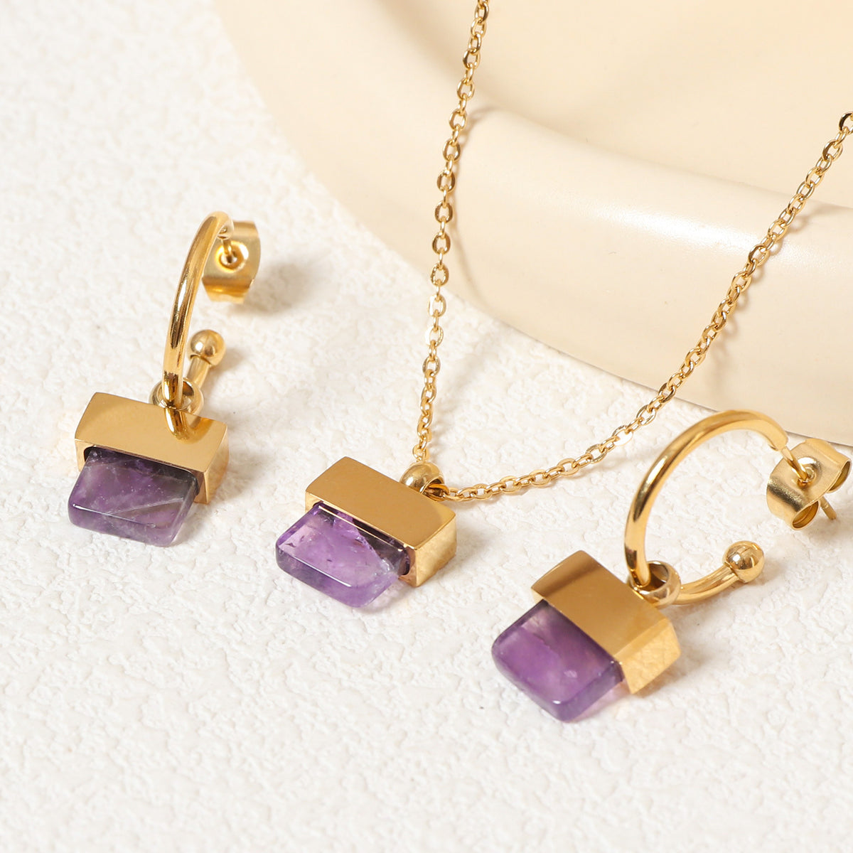 luxury geometric jewelry set featuring a gold pendant necklace and matching square purple stone hoop earrings