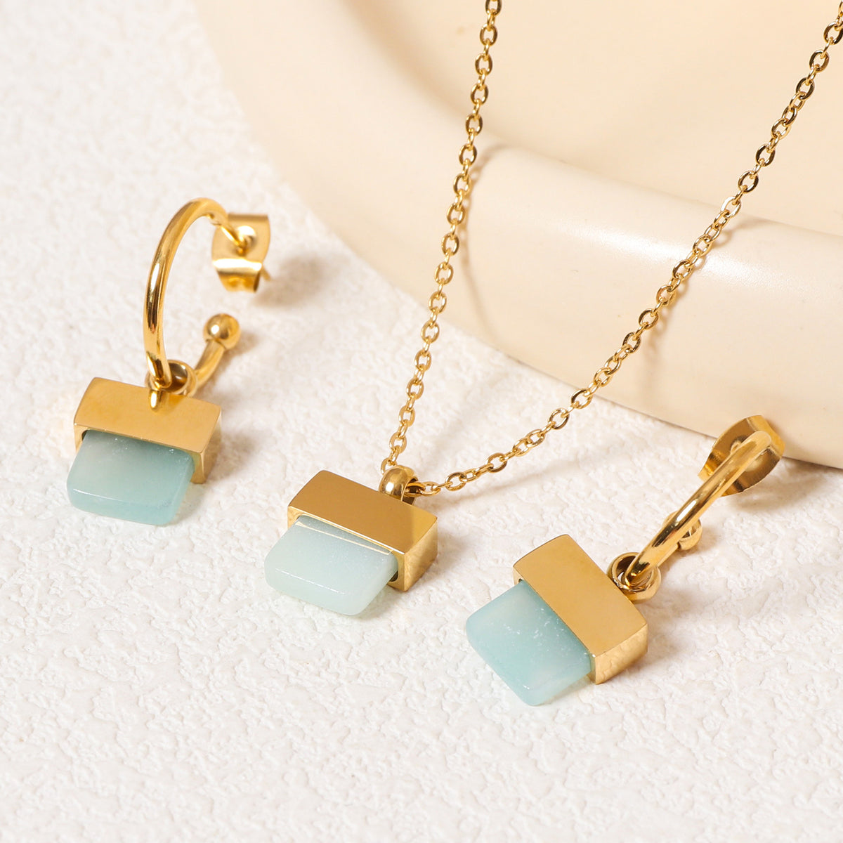 luxury geometric jewelry set featuring a gold pendant necklace and matching square stone hoop earrings