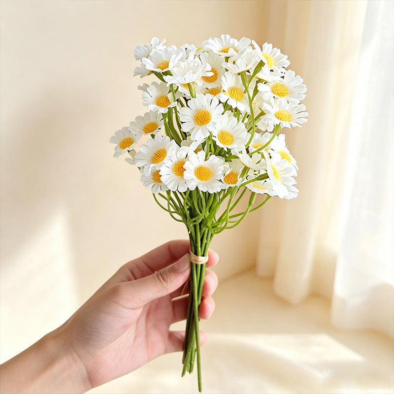 realistic artificial daisy chamomile flower bouquet held by a hand in warm soft indoor lighting