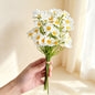 realistic artificial daisy chamomile flower bouquet held by a hand in warm soft indoor lighting