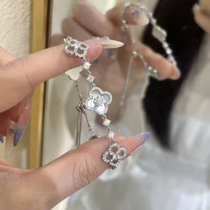 close up look of four leaf clover mother of pearl bracelet with glistening crystal charms being held by a model