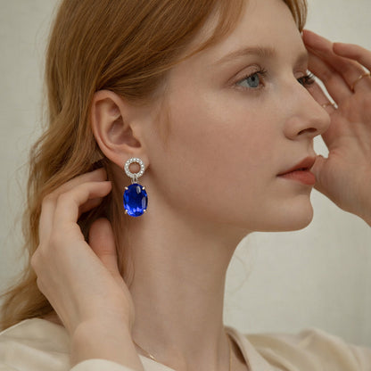 beautiful female model wearing the luxury royal blue sapphire oval drop stud earrings to showcase elegant style