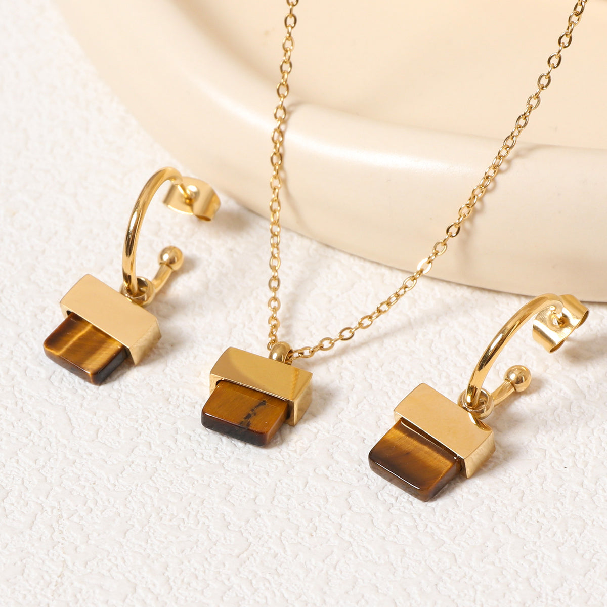 luxury geometric jewelry set featuring a gold pendant necklace and matching square brown stone hoop earrings