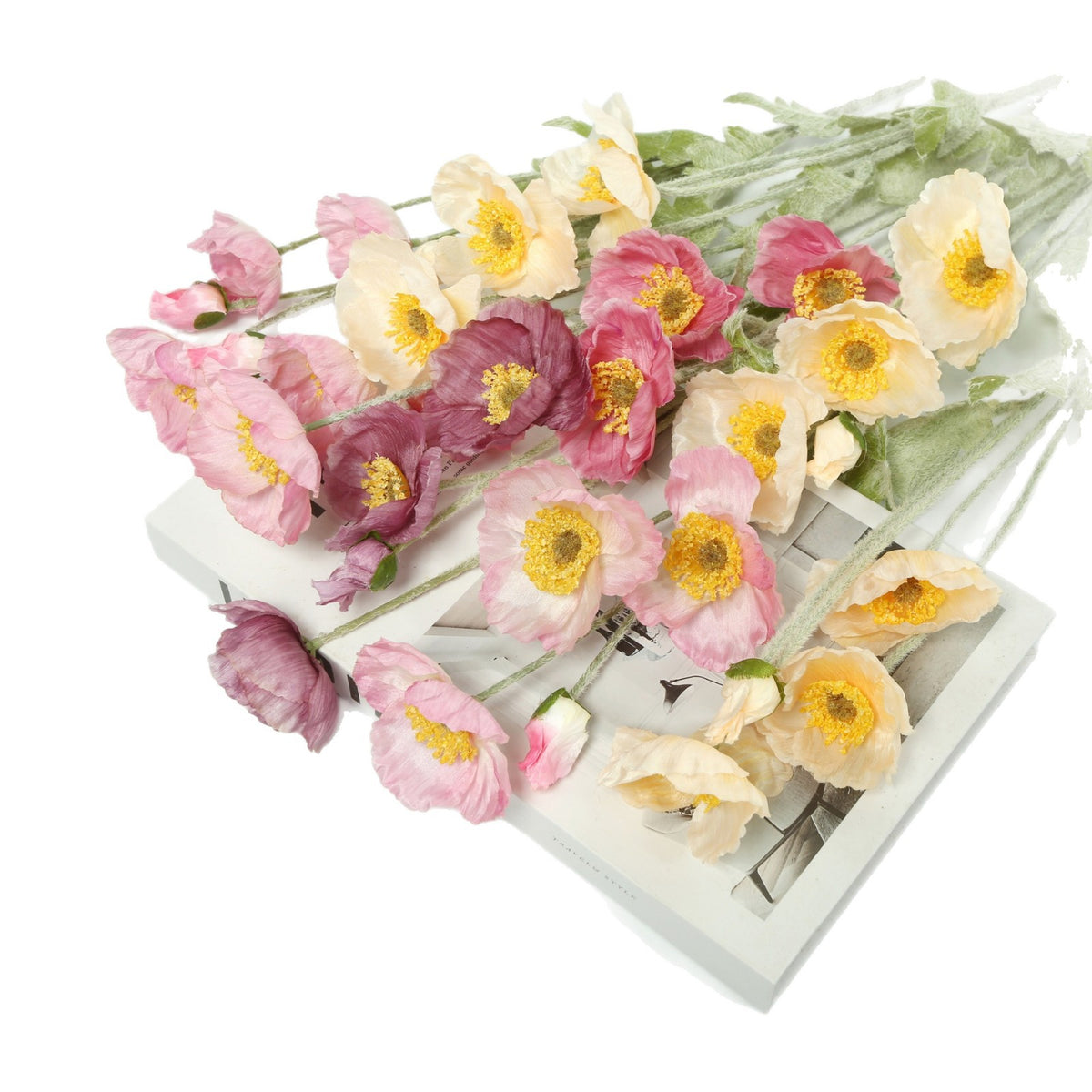 assorted colors of premium realistic artificial poppy flowers flat laid on a white background