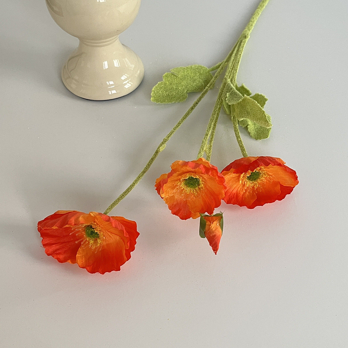 realistic faux silk poppy flowers in bright sunset red color on an aesthetic grey background