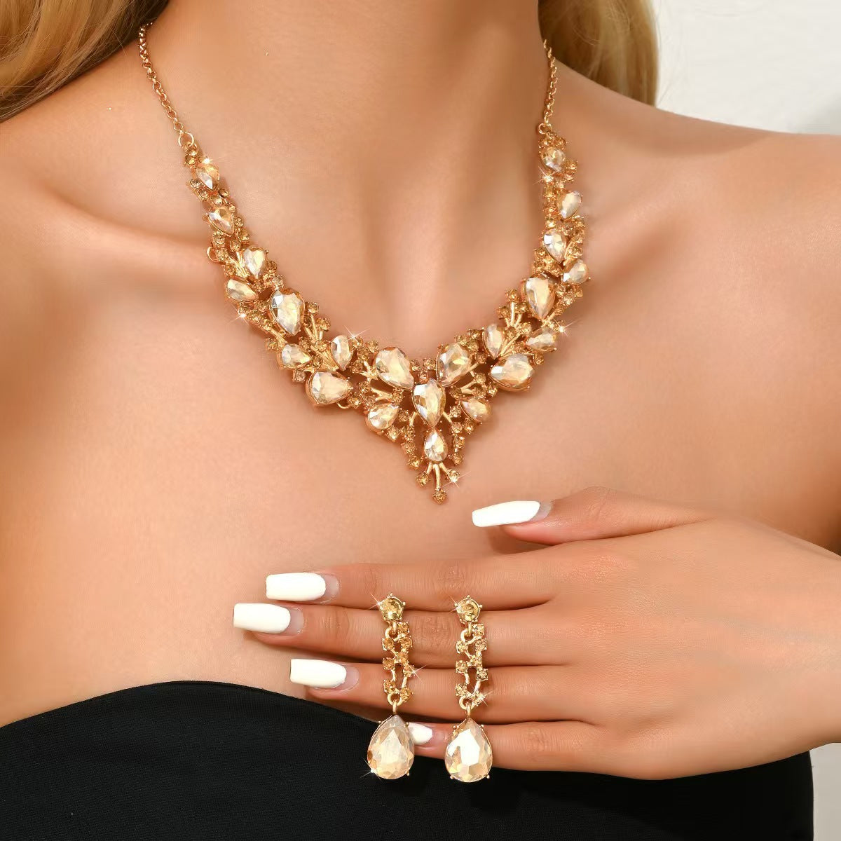 elegant waterdrop crystal bridal jewelry set in gold color showcasing the statement necklace and matching drop earrings on a model