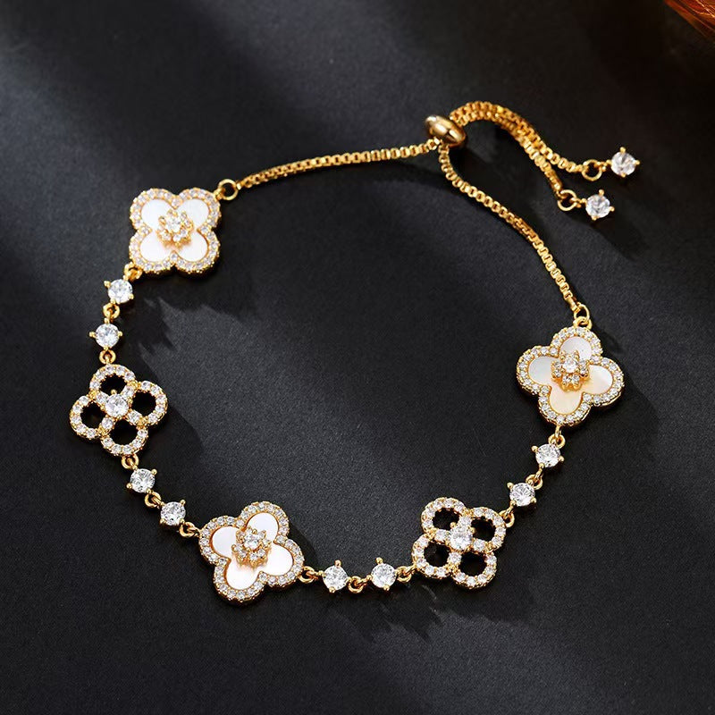 four leaf clover mother of pearl bracelet in classic white color with gold adjustable pull chain on a dark background