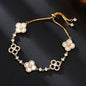 four leaf clover mother of pearl bracelet in classic white color with gold adjustable pull chain on a dark background