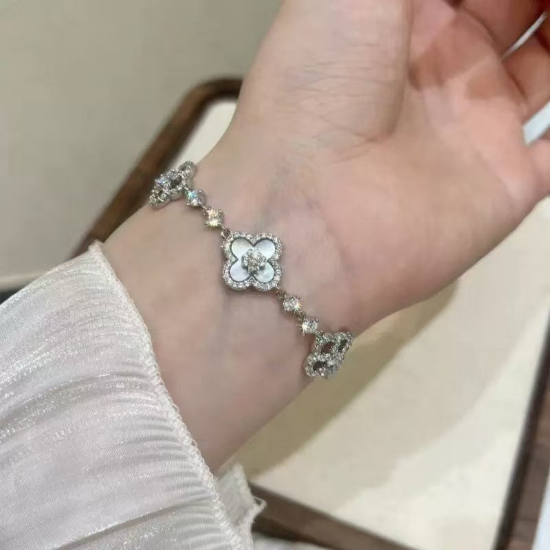 four leaf clover mother of pearl bracelet in classic white color with silver chain worn on a models wrist