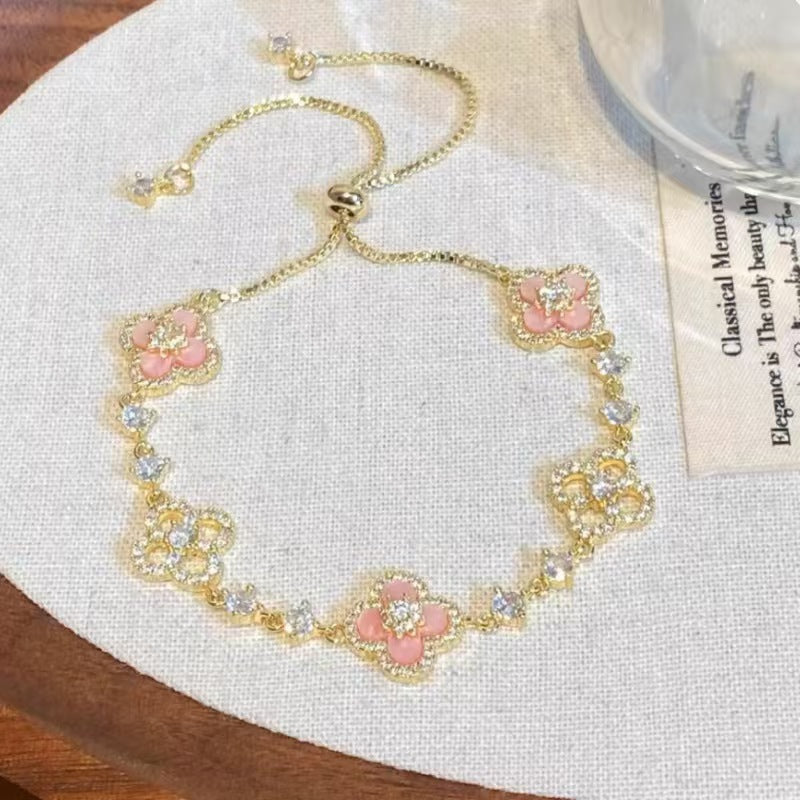 four leaf clover mother of pearl bracelet in gentle pink color with gold adjustable chain on an elegant vintage background card