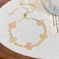 four leaf clover mother of pearl bracelet in gentle pink color with gold adjustable chain on an elegant vintage background card