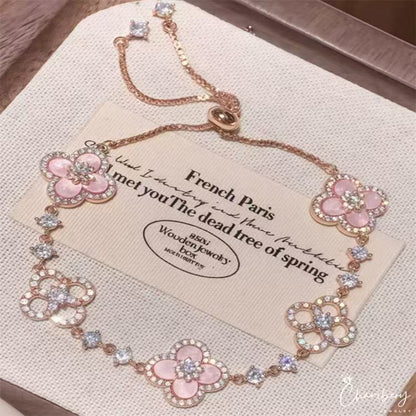 four leaf clover mother of pearl bracelet in gentle pink color with rose gold chain displayed on an elegant vintage background card