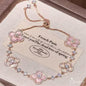 four leaf clover mother of pearl bracelet in gentle pink color with rose gold chain displayed on an elegant vintage background card