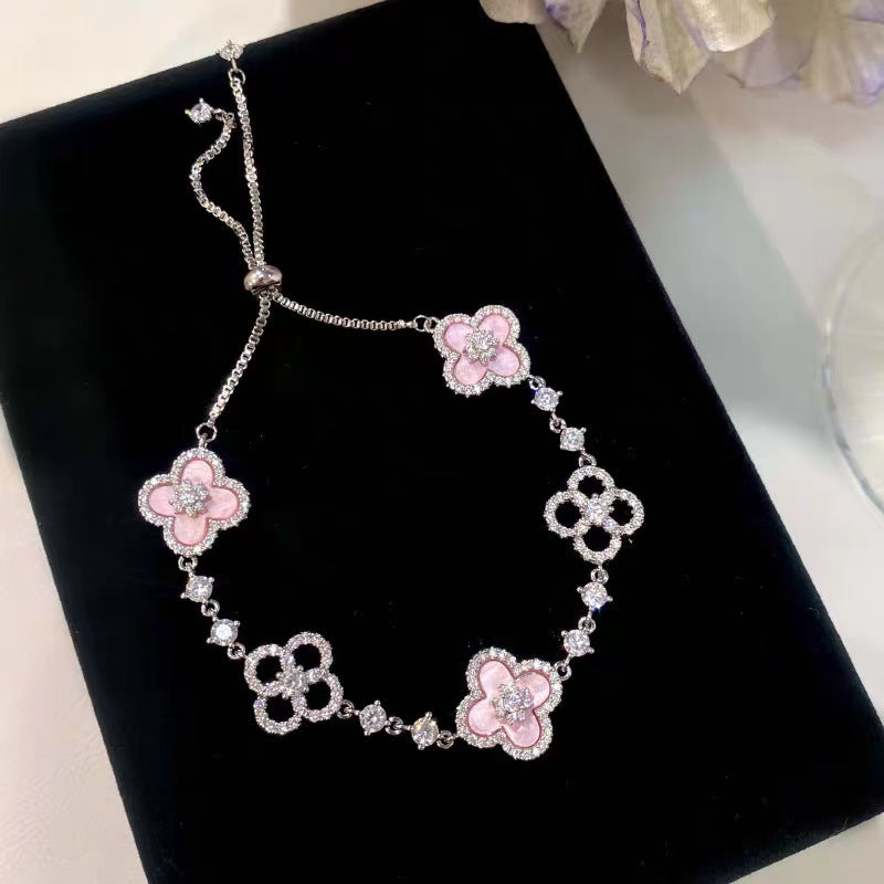 four leaf clover mother of pearl bracelet in gentle pink color with silver adjustable chain on a black display board