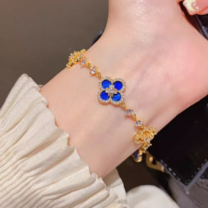 four leaf clover mother of pearl bracelet in royal blue color with gold chain worn on a models wrist