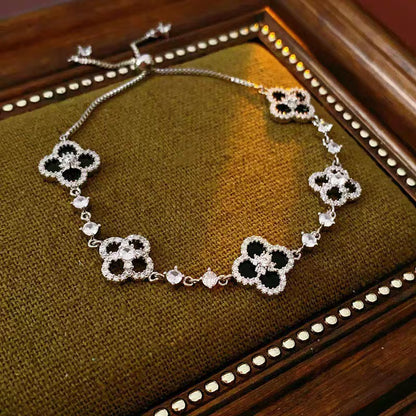 four leaf clover mother of pearl bracelet in sleek black color with silver adjustable chain on a vintage velvet tray