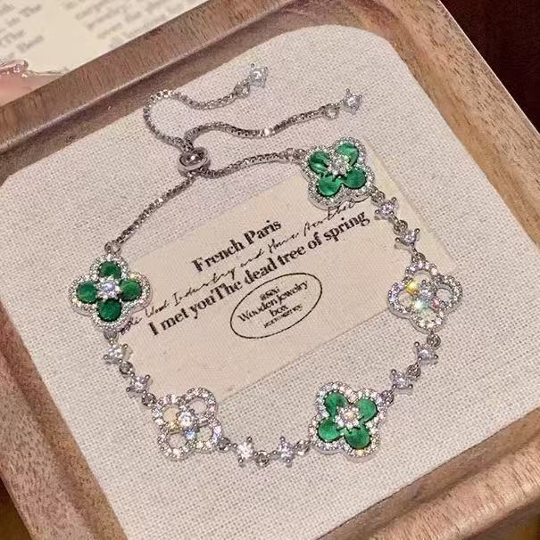 four leaf clover mother of pearl bracelet in vibrant emerald green color with silver adjustable chain on an elegant vintage background card