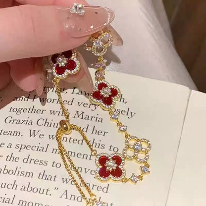 four leaf clover mother of pearl bracelet in vibrant red color with gold adjustable chain held by a model