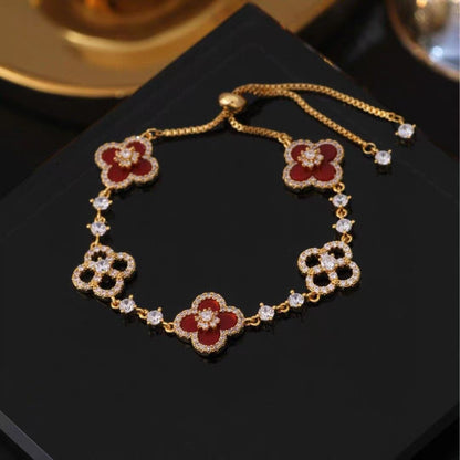 four leaf clover mother of pearl bracelet in vibrant red color with gold adjustable chain on a dark display tray