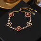 four leaf clover mother of pearl bracelet in vibrant red color with gold adjustable chain on a dark display tray