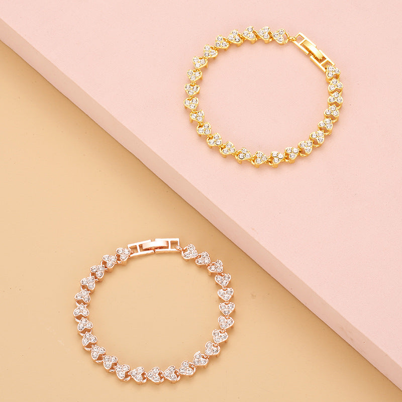 gold and rose gold heart shape tennis bracelets with sparkling iced out crystals displayed together