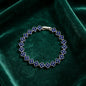 luxury four leaf clover crystal charm bracelet with royal blue rhinestone gems on dark green velvet cushion
