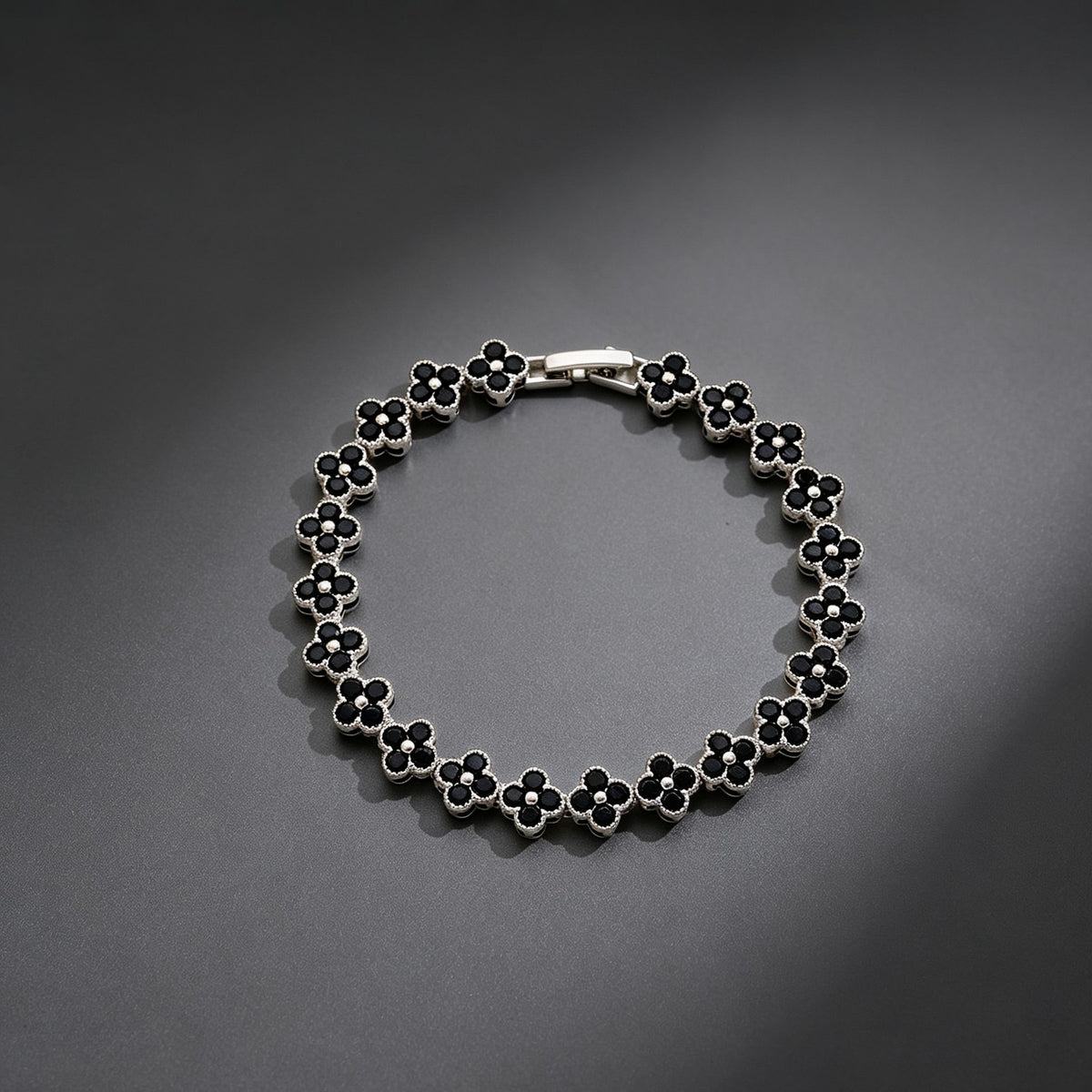luxury four leaf clover crystal charm bracelet with sleek black rhinestone gems on a clean dark grey background
