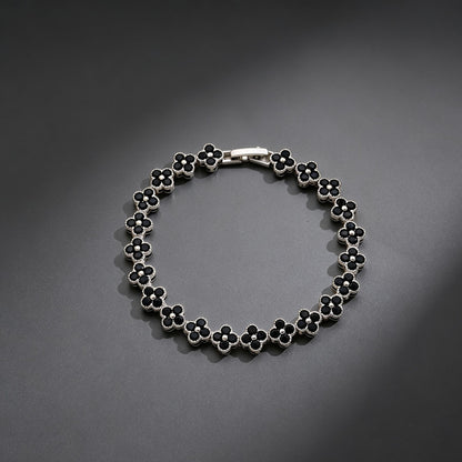 luxury four leaf clover crystal charm bracelet with sleek black rhinestone gems on a clean dark grey background