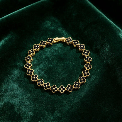 luxury four leaf clover crystal charm bracelet with sleek black rhinestone gems on dark green velvet cushion